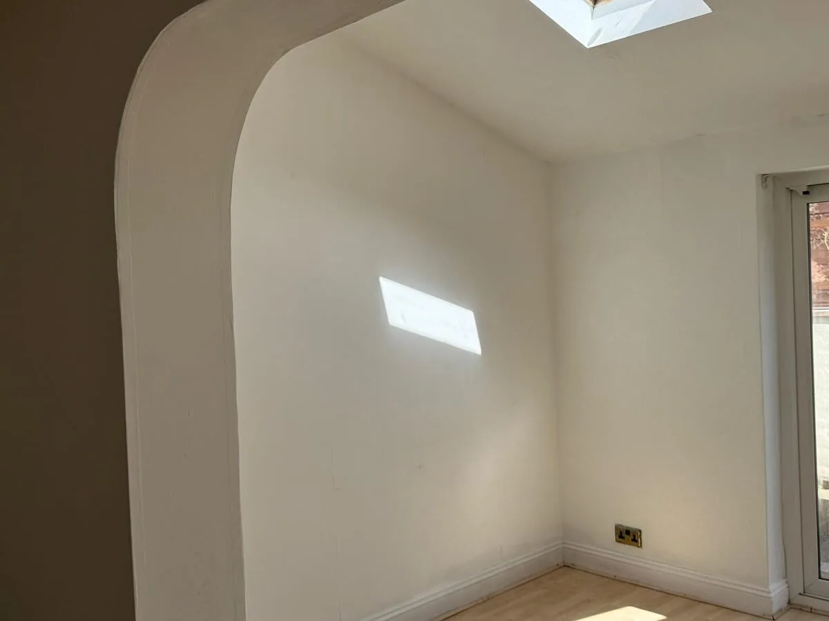 Freshly painted room corner with a crisp white arched doorway