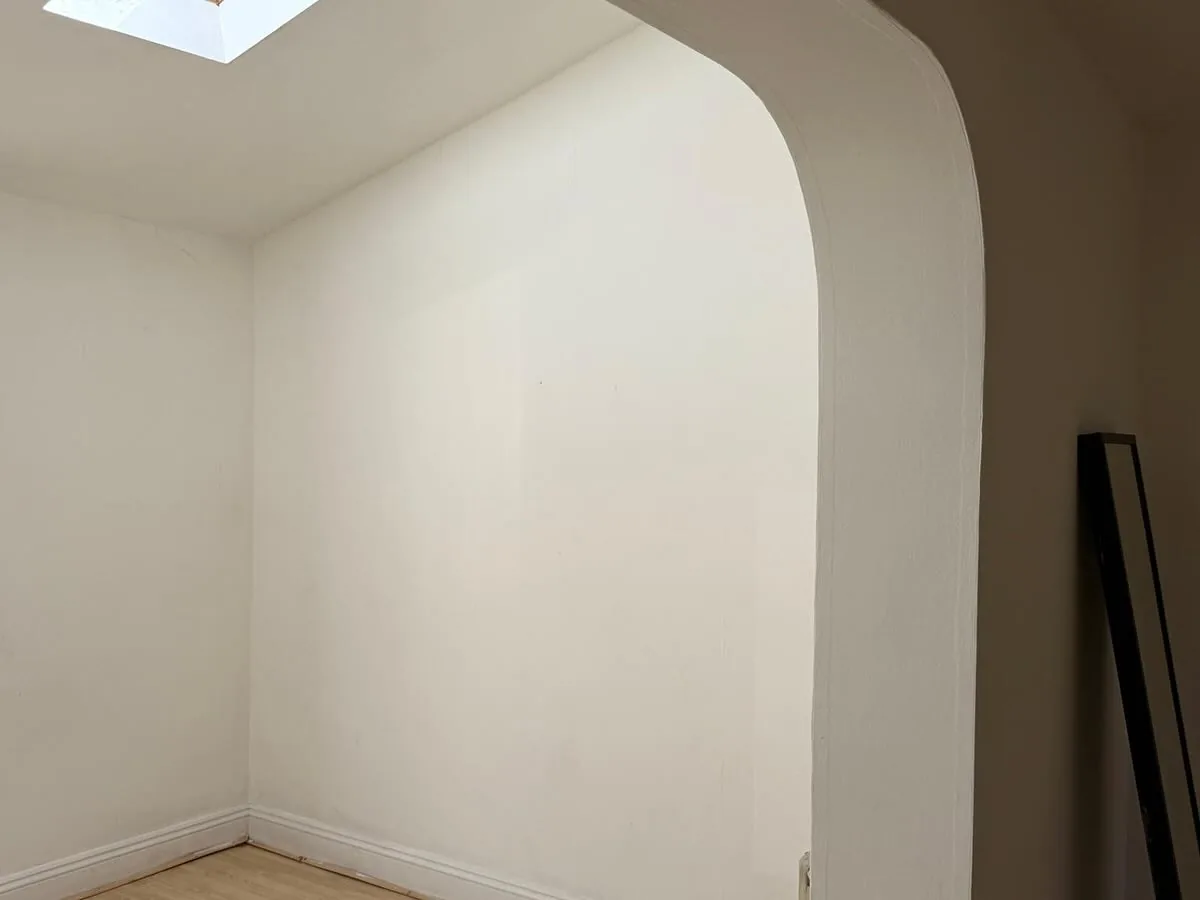 A bright, freshly painted room with a crisp white arched doorway